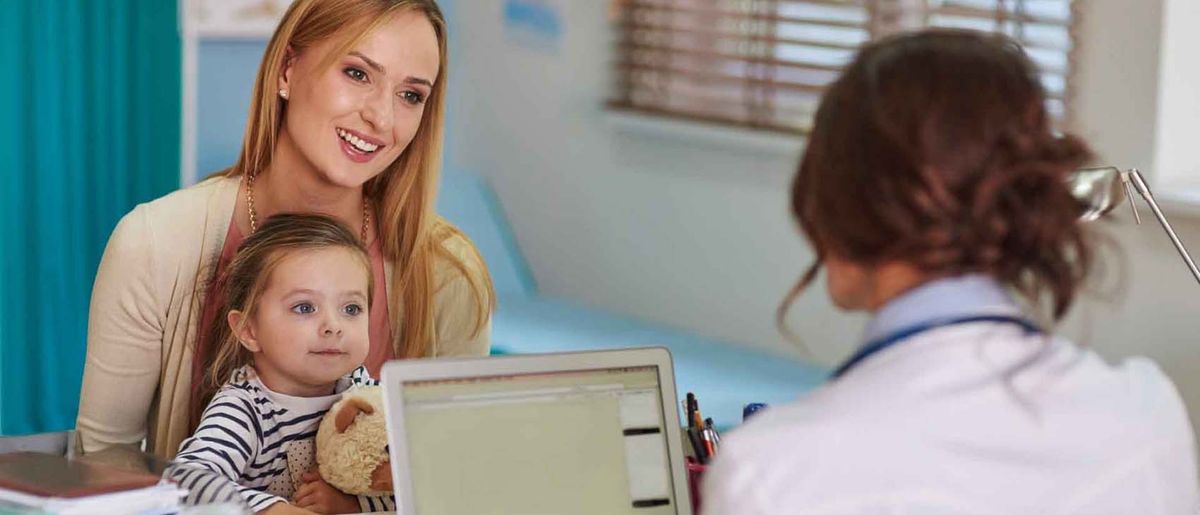 Mother and young child at doctor's office during medical consultation with healthcare provider.