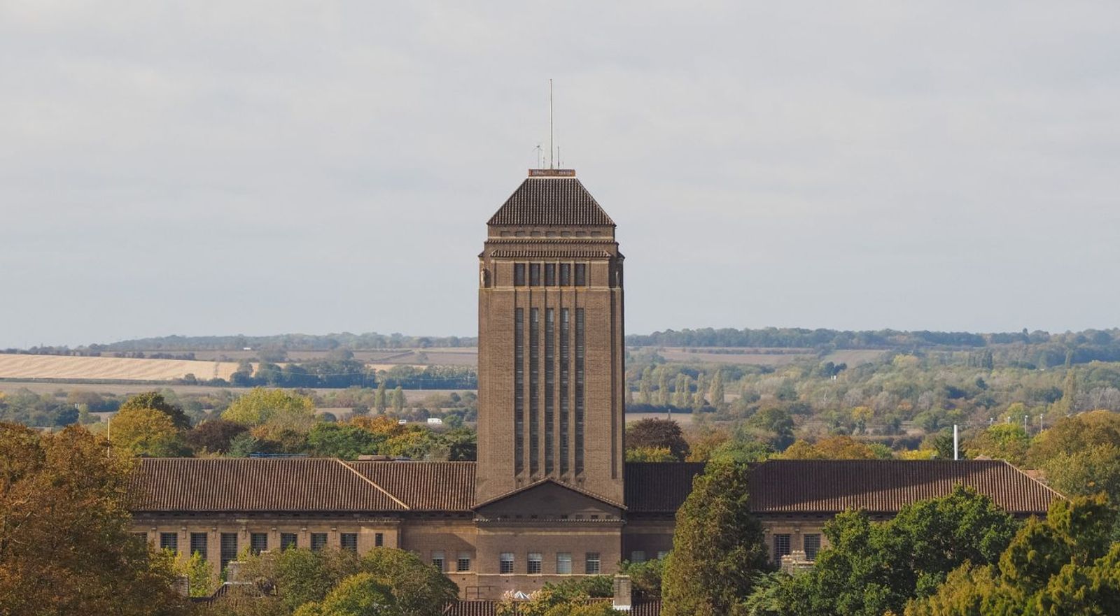 Art Deco brick building with dome tower overlooking rural countryside landscape.