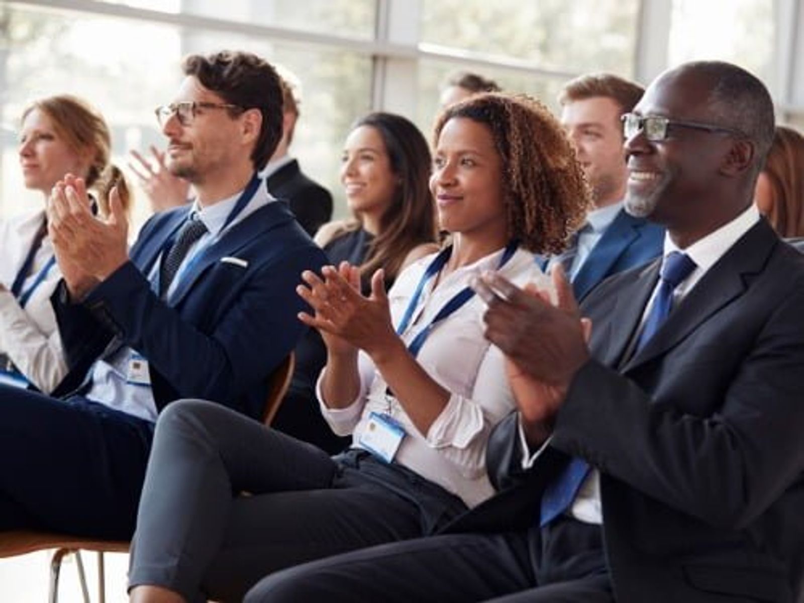 Grupo de diversos profesionales de negocios aplaudiendo durante una presentación en conferencia o seminario.
