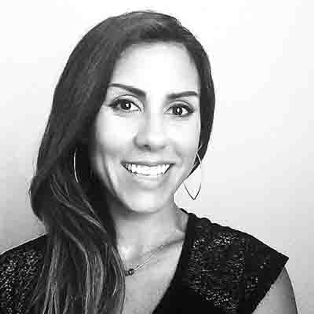Black and white headshot of a smiling woman with long dark hair and hoop earrings.