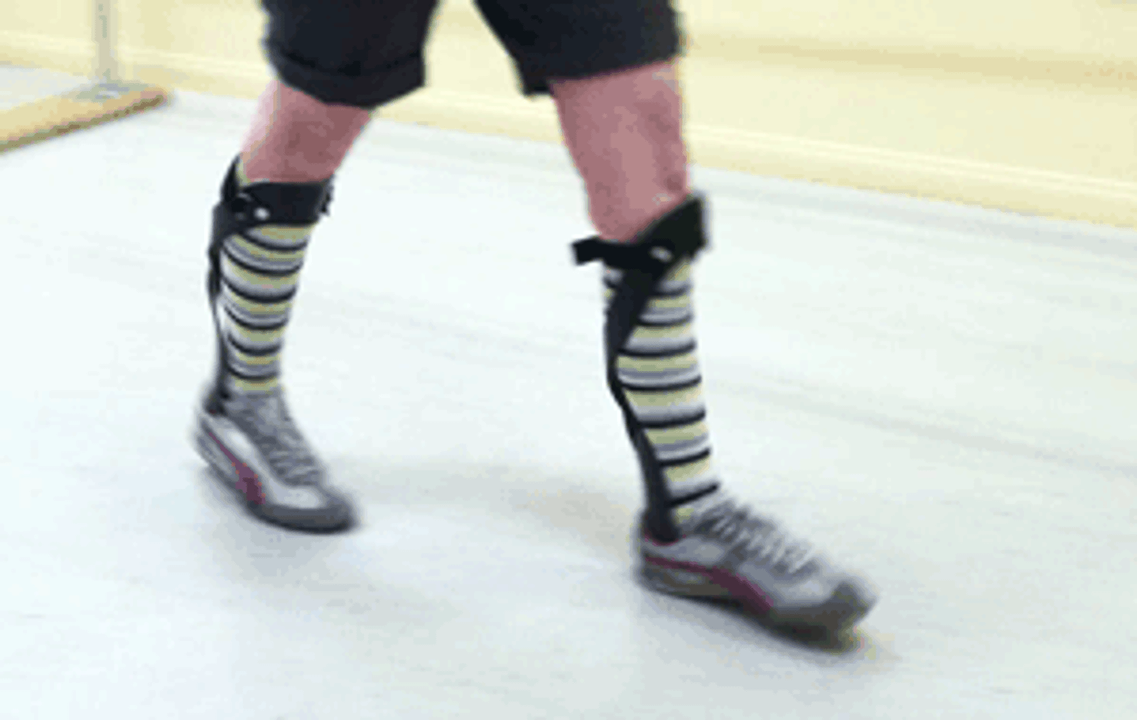 Person wearing striped knee-high socks standing on ice skating rink.