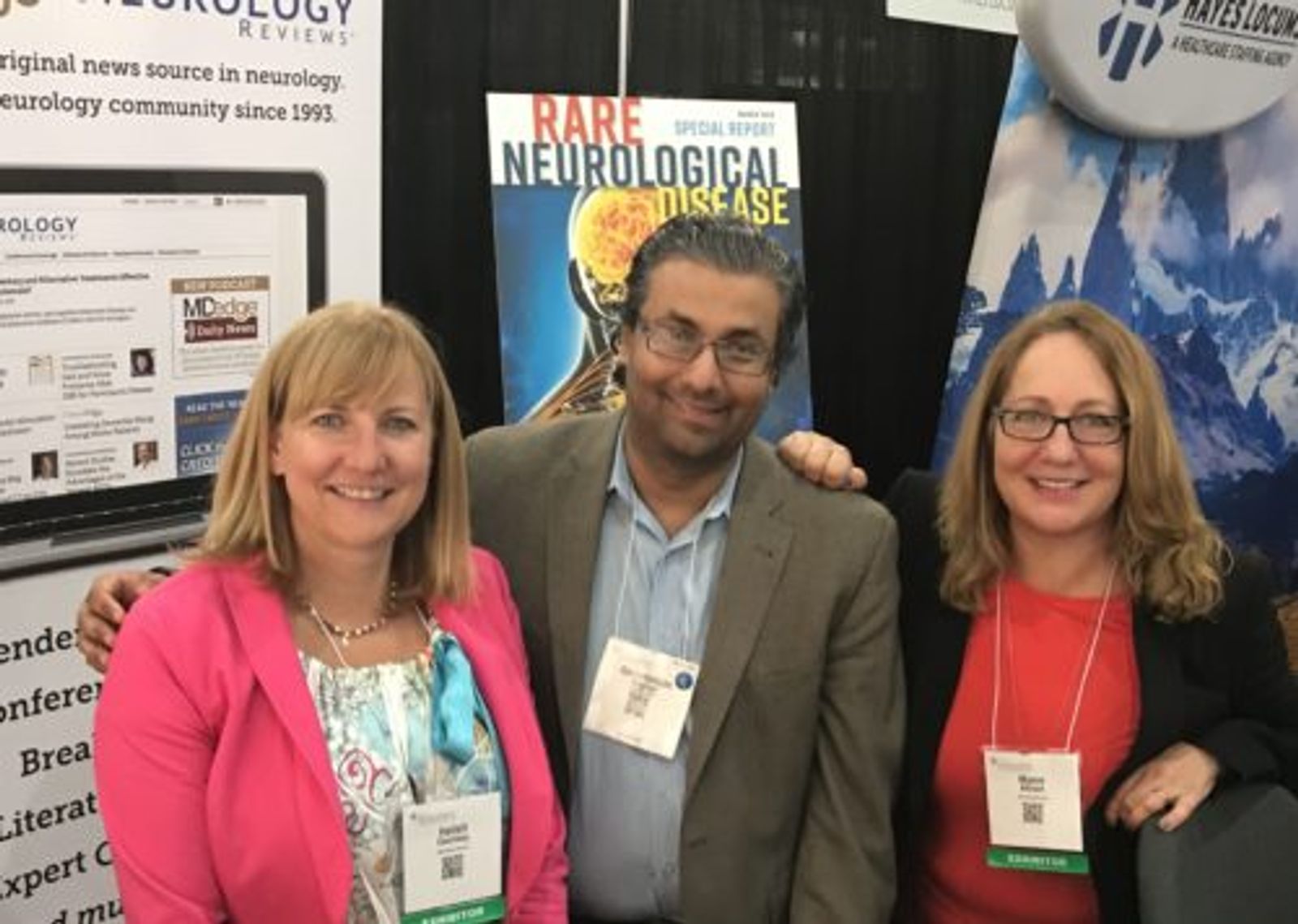 Three professionals at conference booth displaying "Rare Neurological Disease" materials and signage.