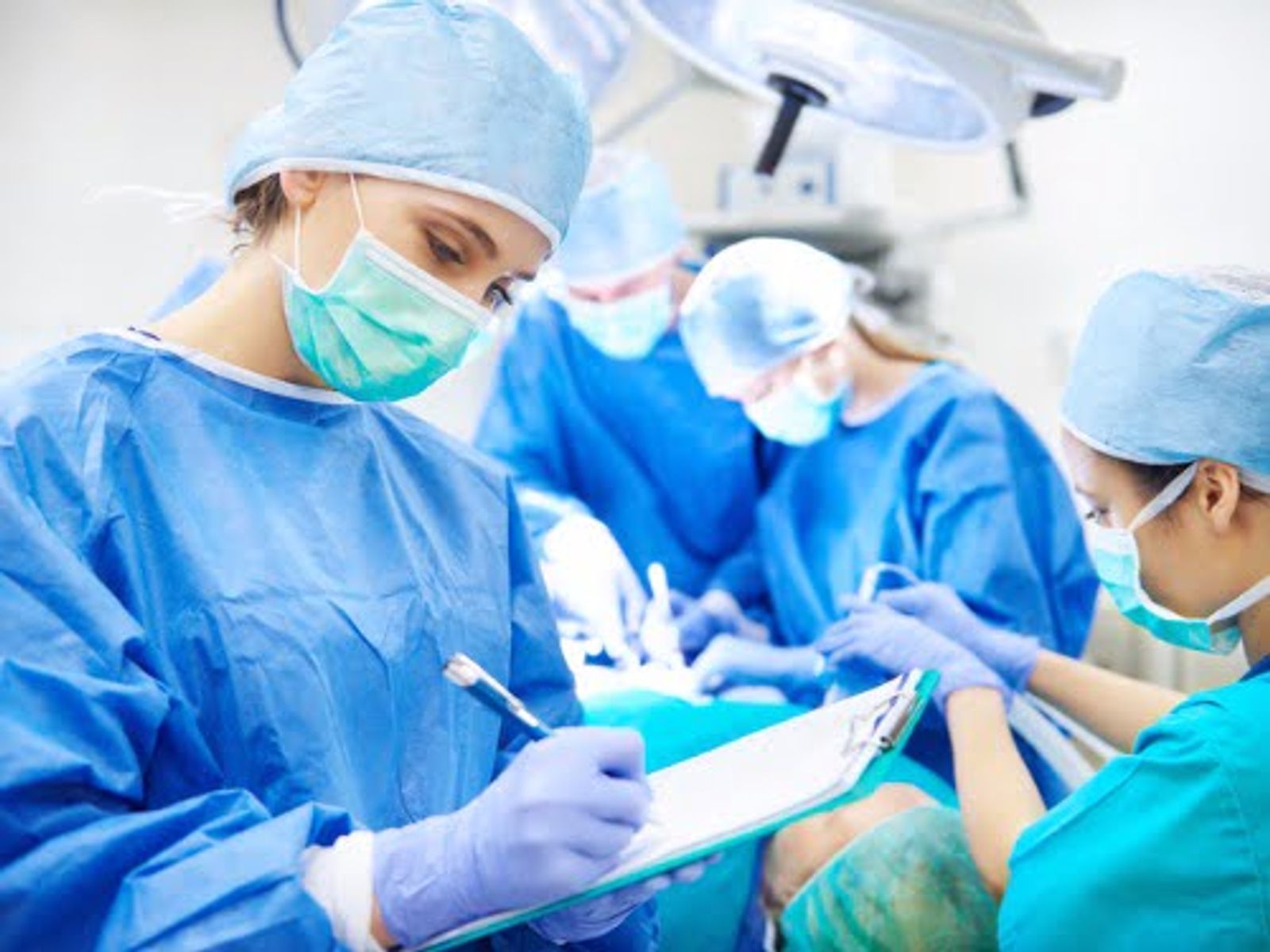 Surgical team in blue scrubs and masks performing operation in sterile environment.