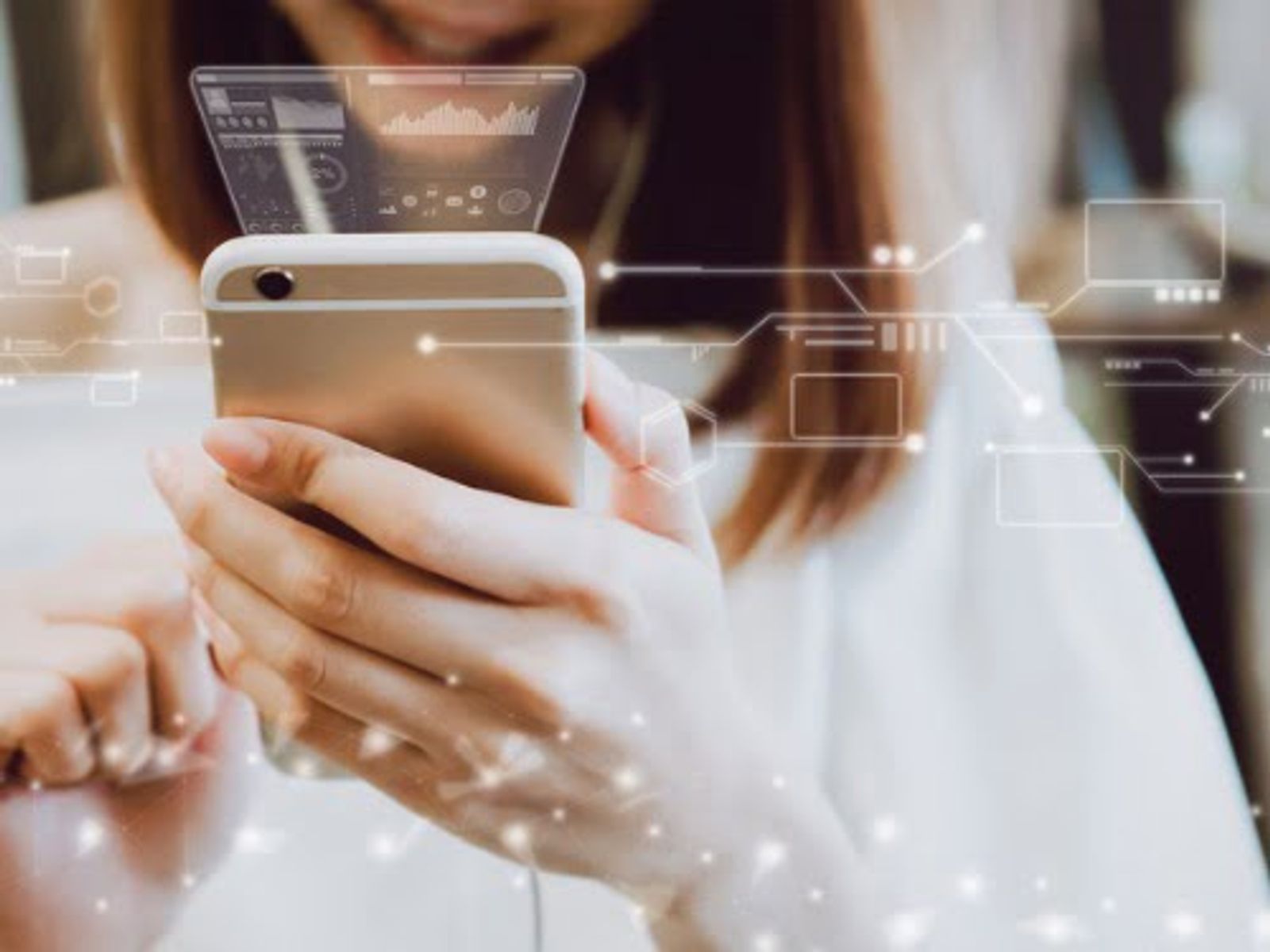 Mujer sosteniendo un teléfono inteligente con una interfaz digital y gráficos de visualización de datos.
