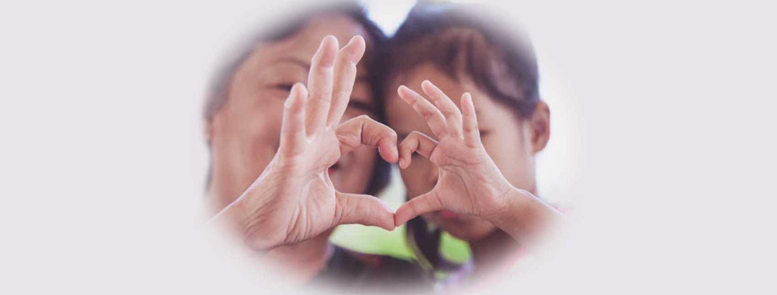 Two people making a heart shape with their hands together