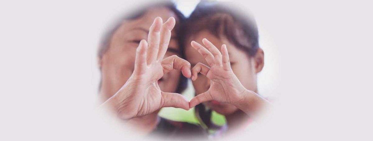 Two people making a heart shape with their hands together
