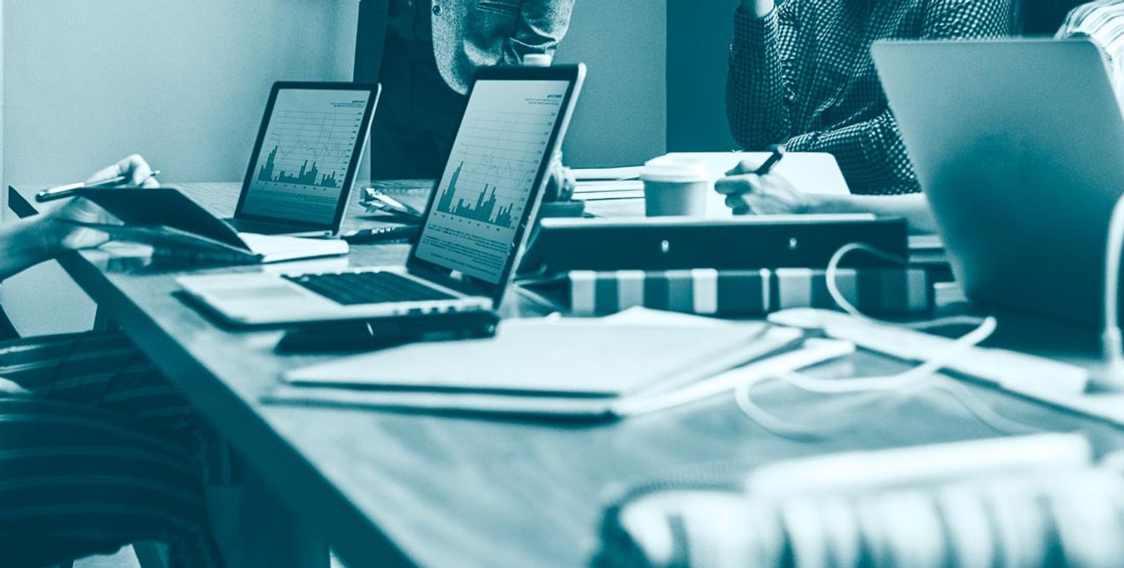 Business team reviewing financial data on multiple devices at conference table