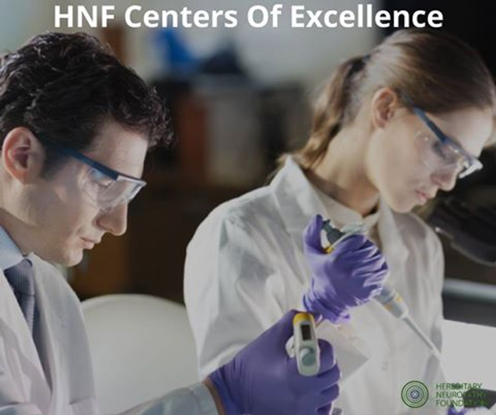 Two researchers in lab coats and safety glasses examine a sample in a laboratory setting. "HNF Centers Of Excellence" text visible at top.