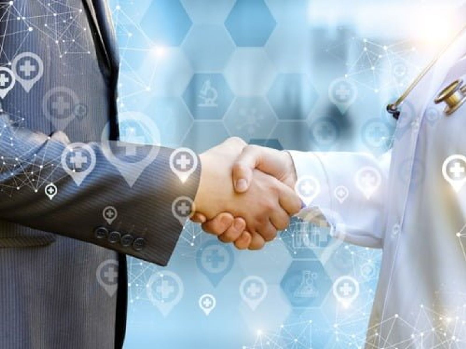 Two businesspeople shaking hands with digital healthcare icons and network overlay on blue background.