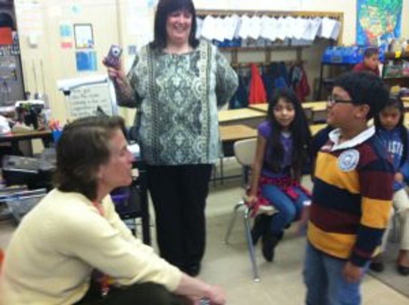 Teacher leads classroom activity with students gathered in circle formation.