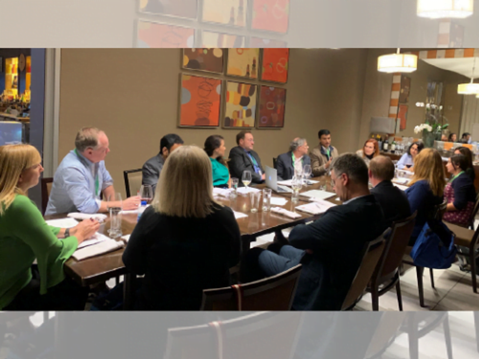 Group of people seated around a long conference table during a business meeting.