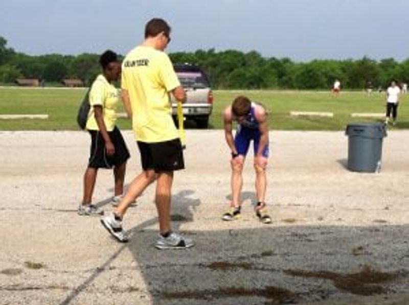 Coach in yellow shirt instructs young athletes during outdoor training session.
