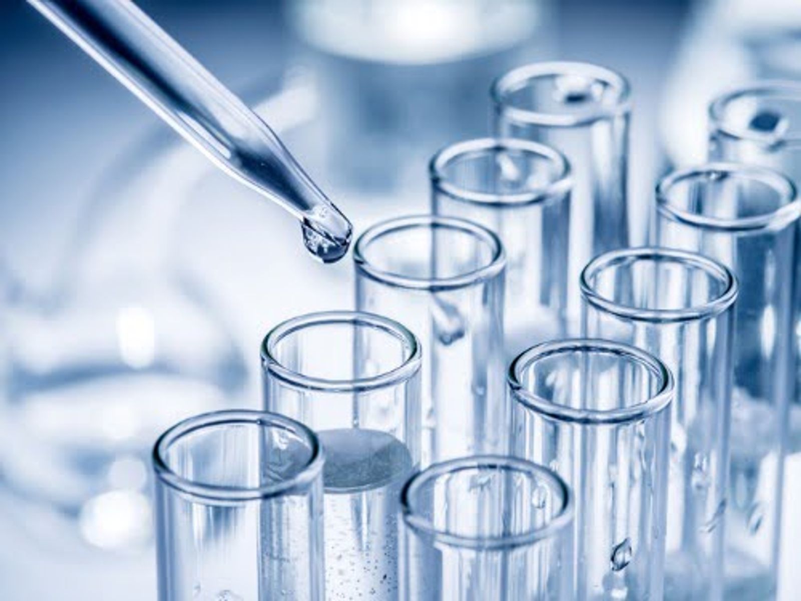 Pipette dropping liquid into laboratory test tubes arranged in a row