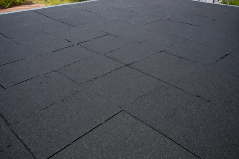 Close view of a dark flat roof membrane with overlapping sheet edges