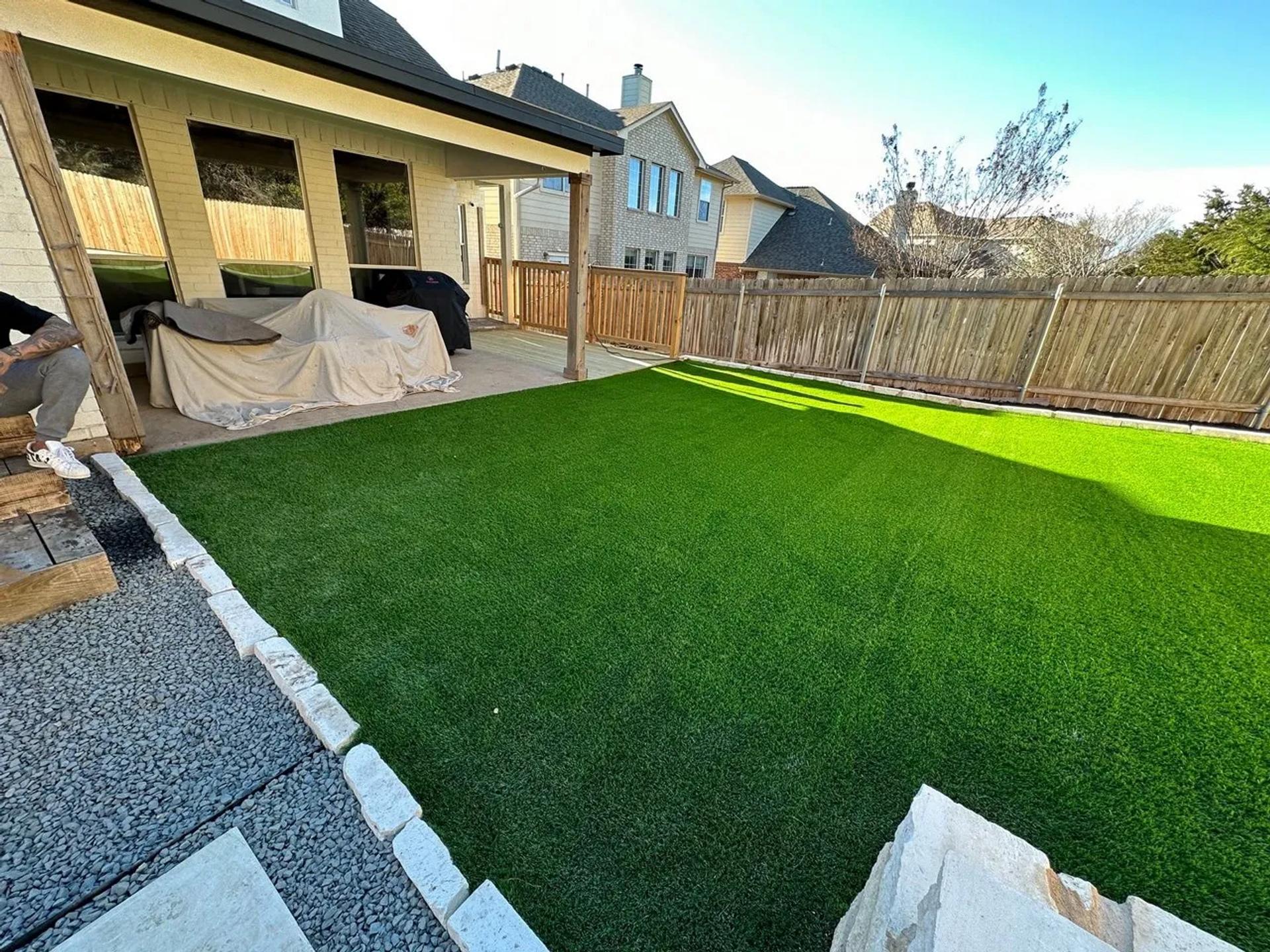 A back yard with artificial turf and a covered outdoor furniture