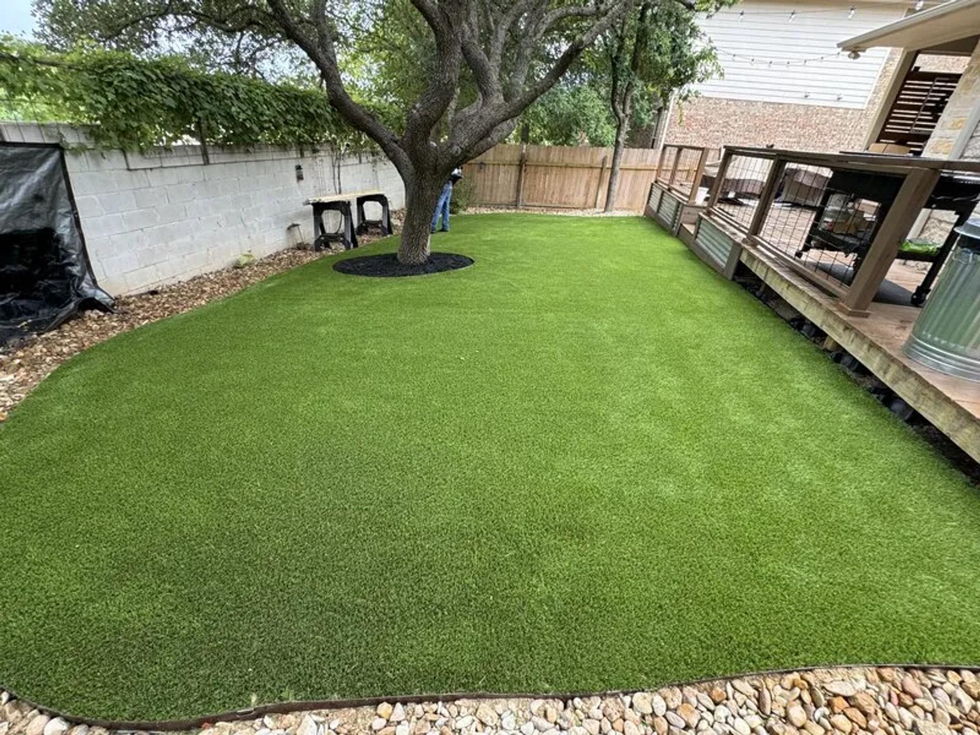 Artificial turf in a back yard with rock around it