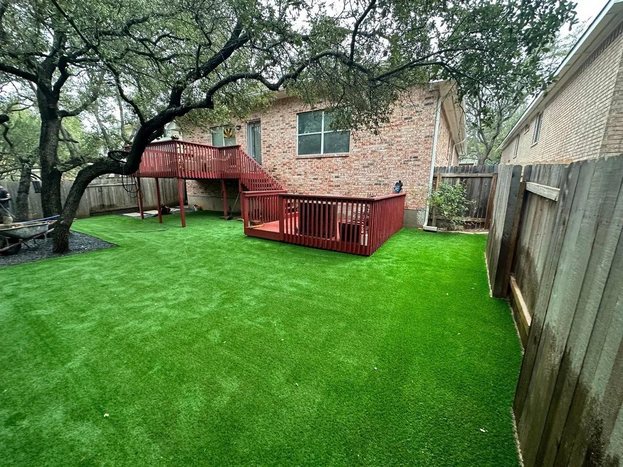 Backyard with artificial turf and a red deck