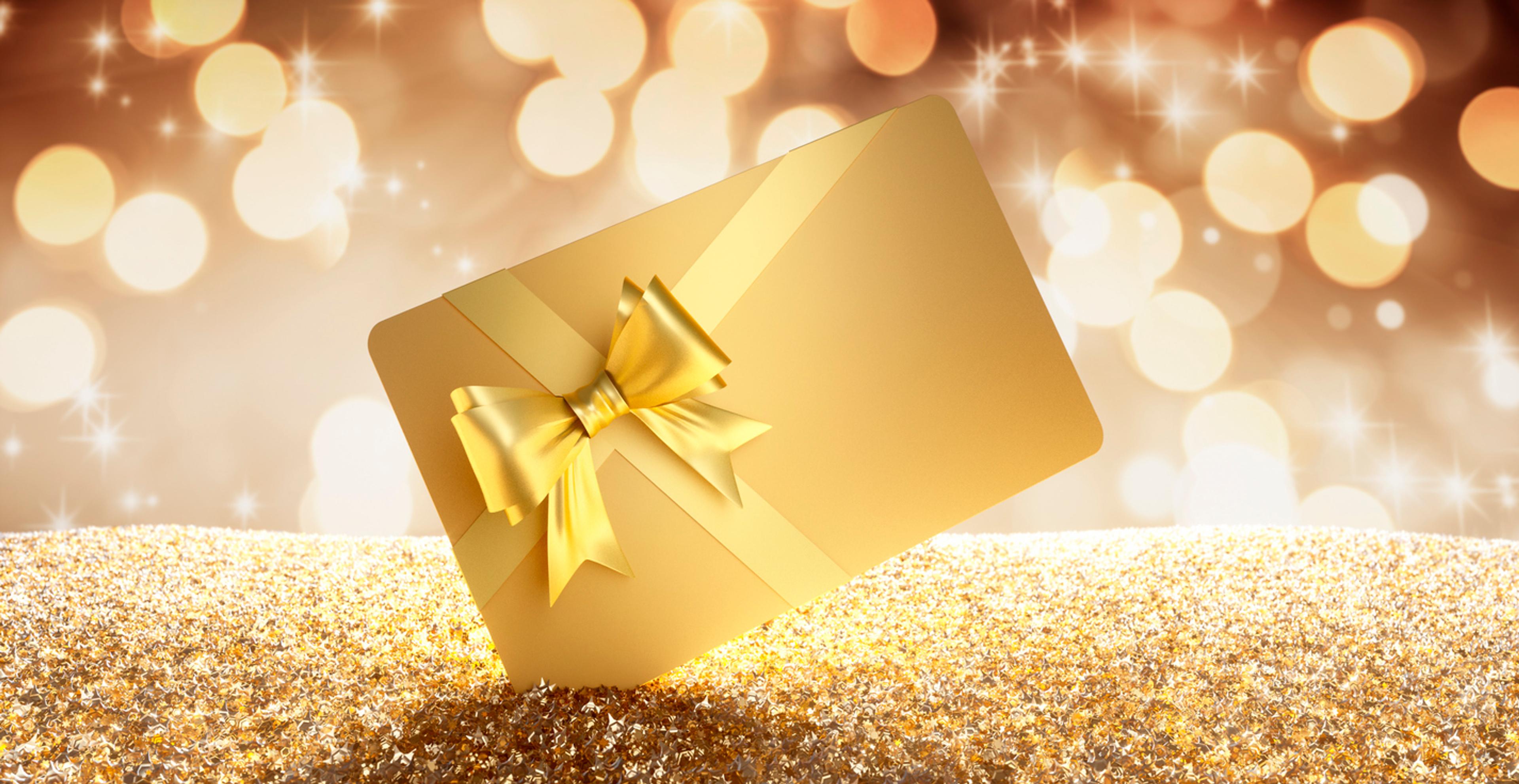 bilde av et gavekort i gull med gullsløyfe med gylne lys i bakgrunnen