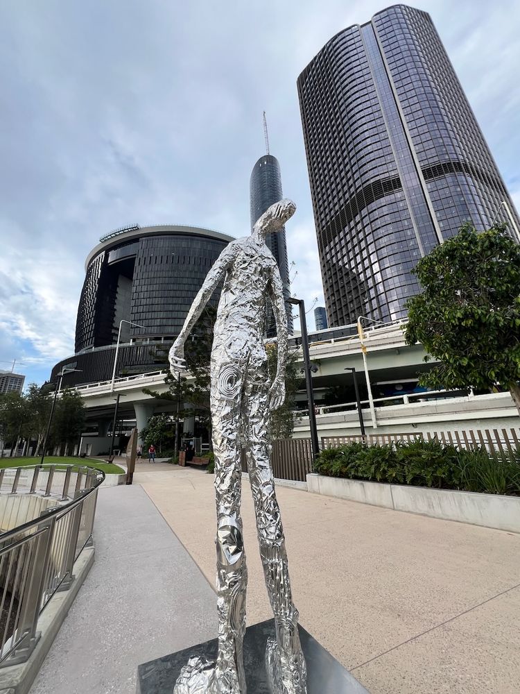 human sculpture looking up at skyscrapers