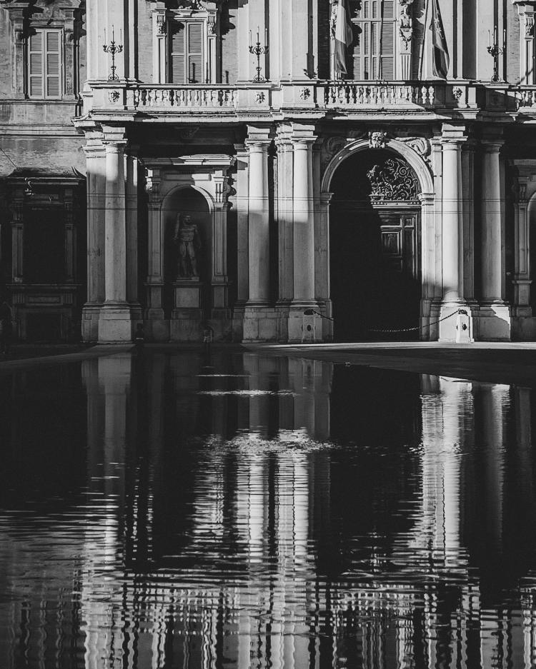 shadows on building with water reflection in black and white