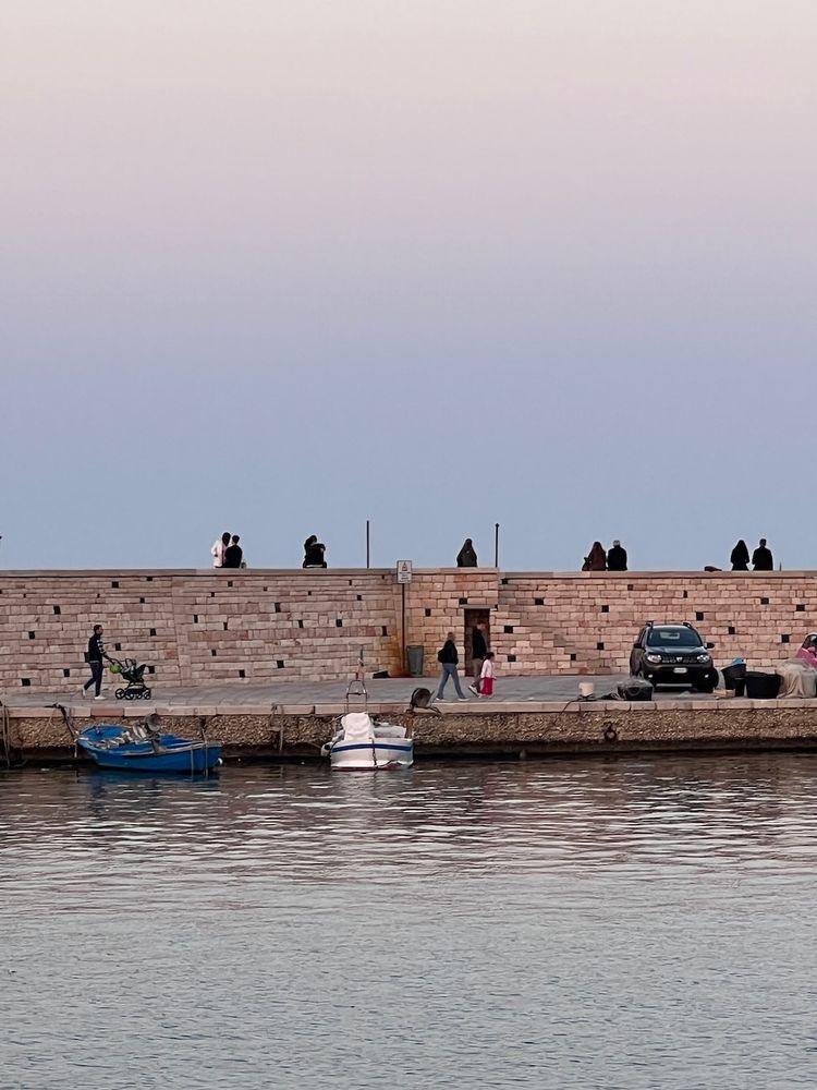 people sitting on harbor wall