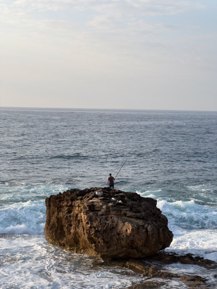 man fishing from rock in ocean