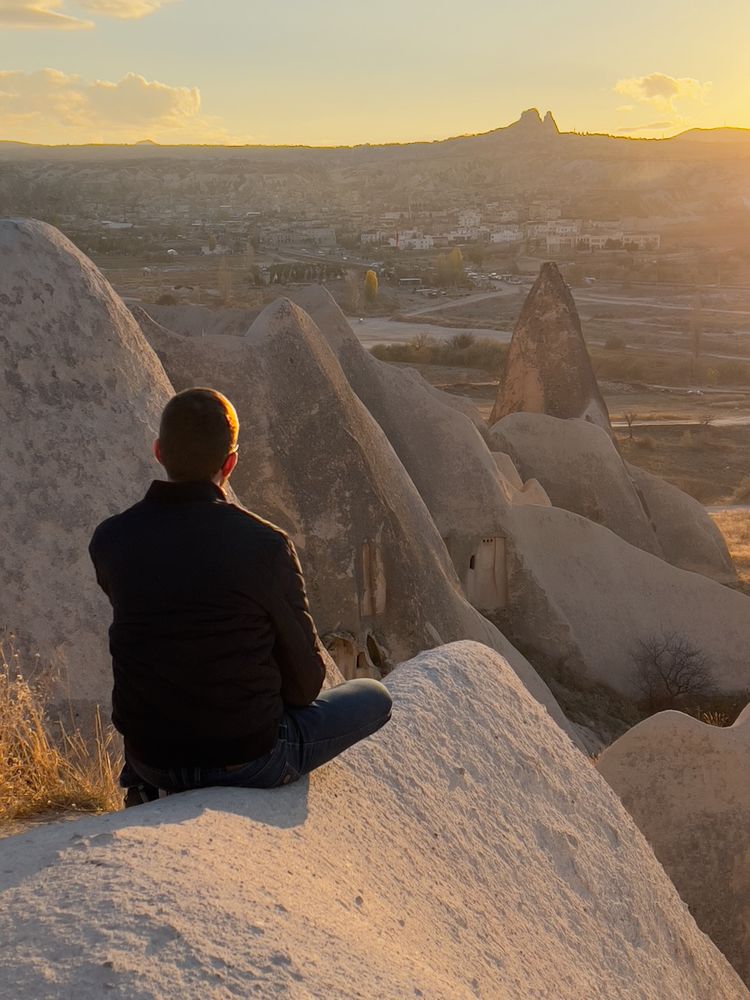 man sitting on rock watching sunset