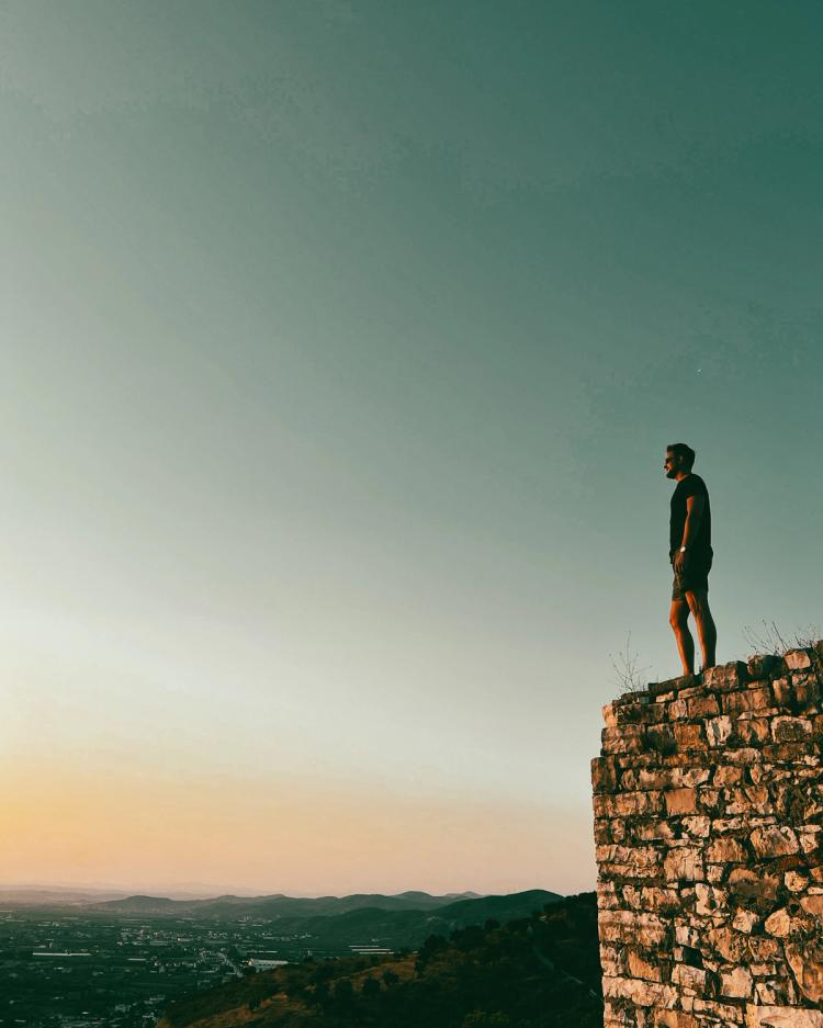 man standing on ledge at sunset