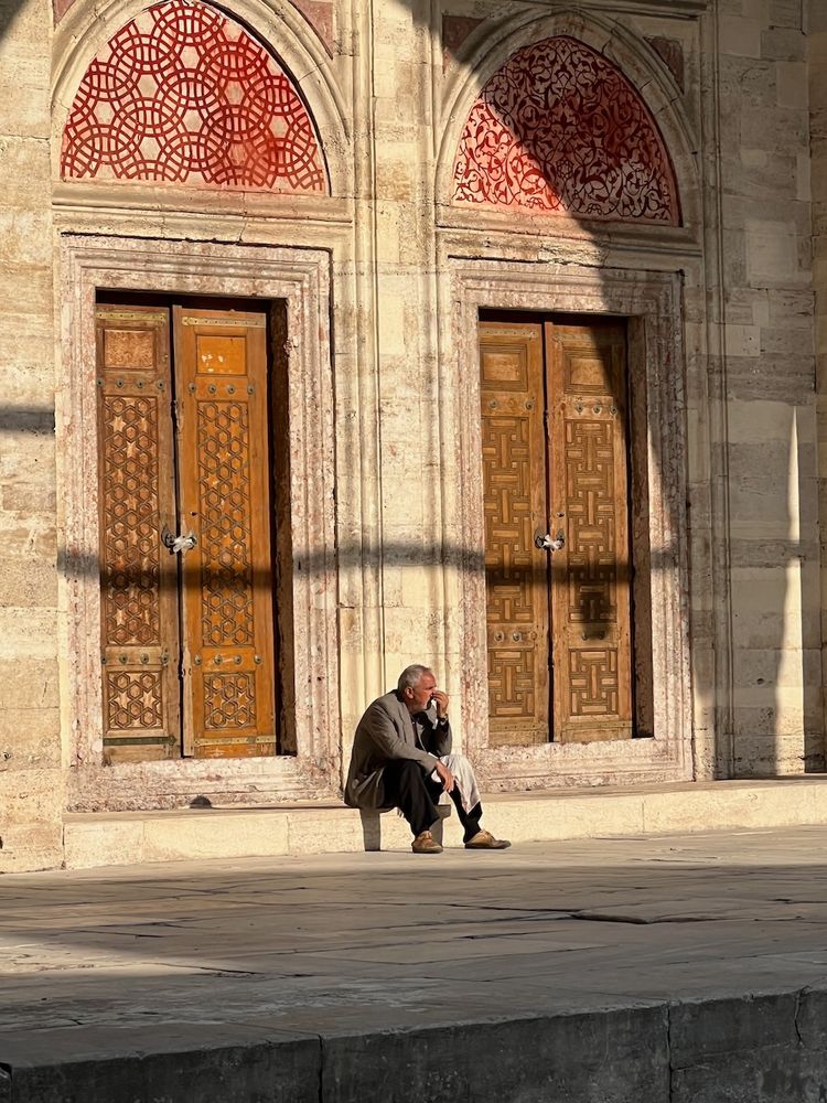man sitting in sun at mosque