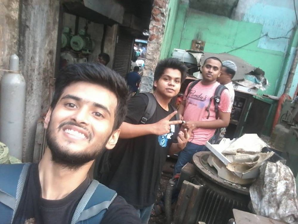 Arko taking a selfie with Hirok in the background at a junkyard