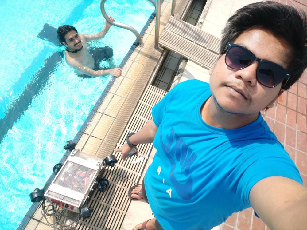 Adnan taking a poolside selfie with Duburi 2 beside him and Sakib swimming in the background during testing.