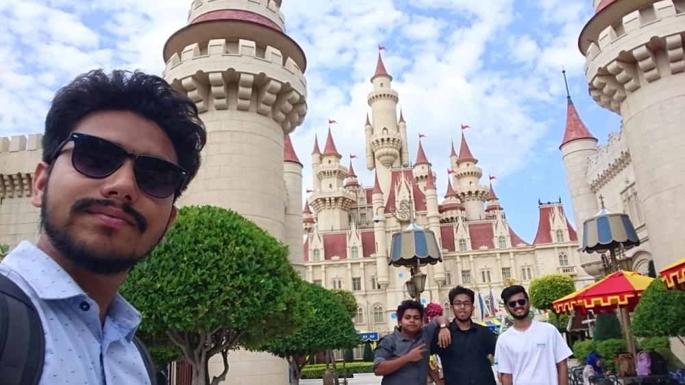 A selfie in front of Far Far Away Castle at Universal Studios Singapore, with three teammates visible in the background
