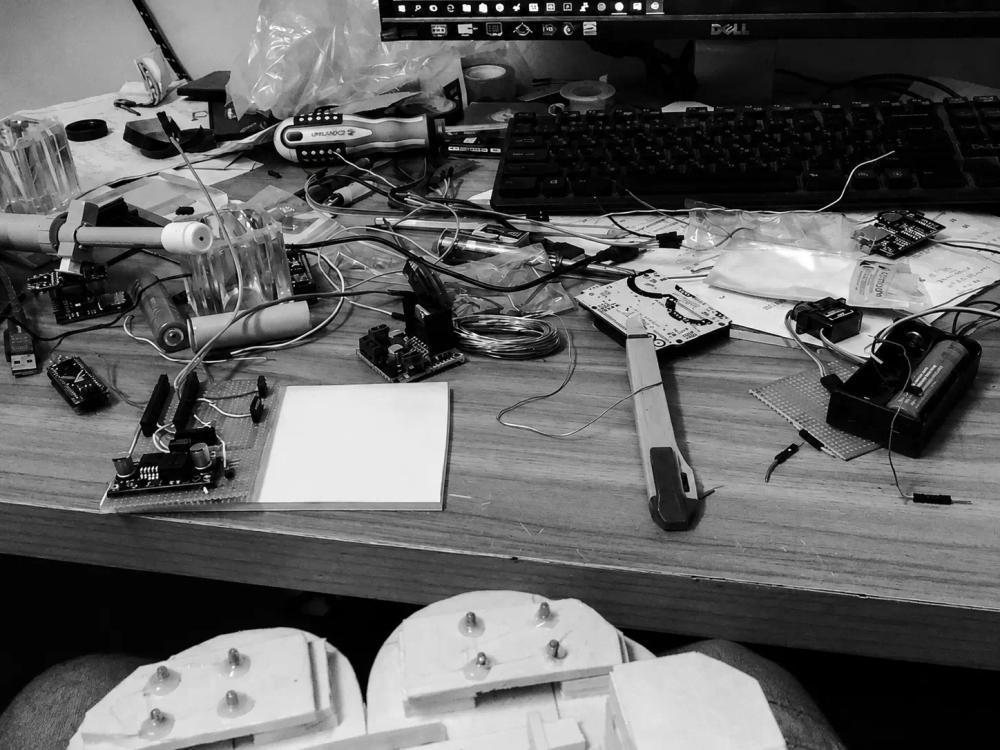 A cluttered electronics workbench full of robotics components, 2016.