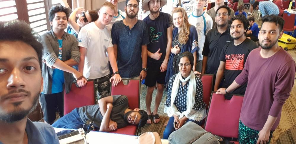 Fahim taking a selfie with Arko asleep beside him, and Adnan, Elham, Shemonto, Sakib, and Riyad in frame