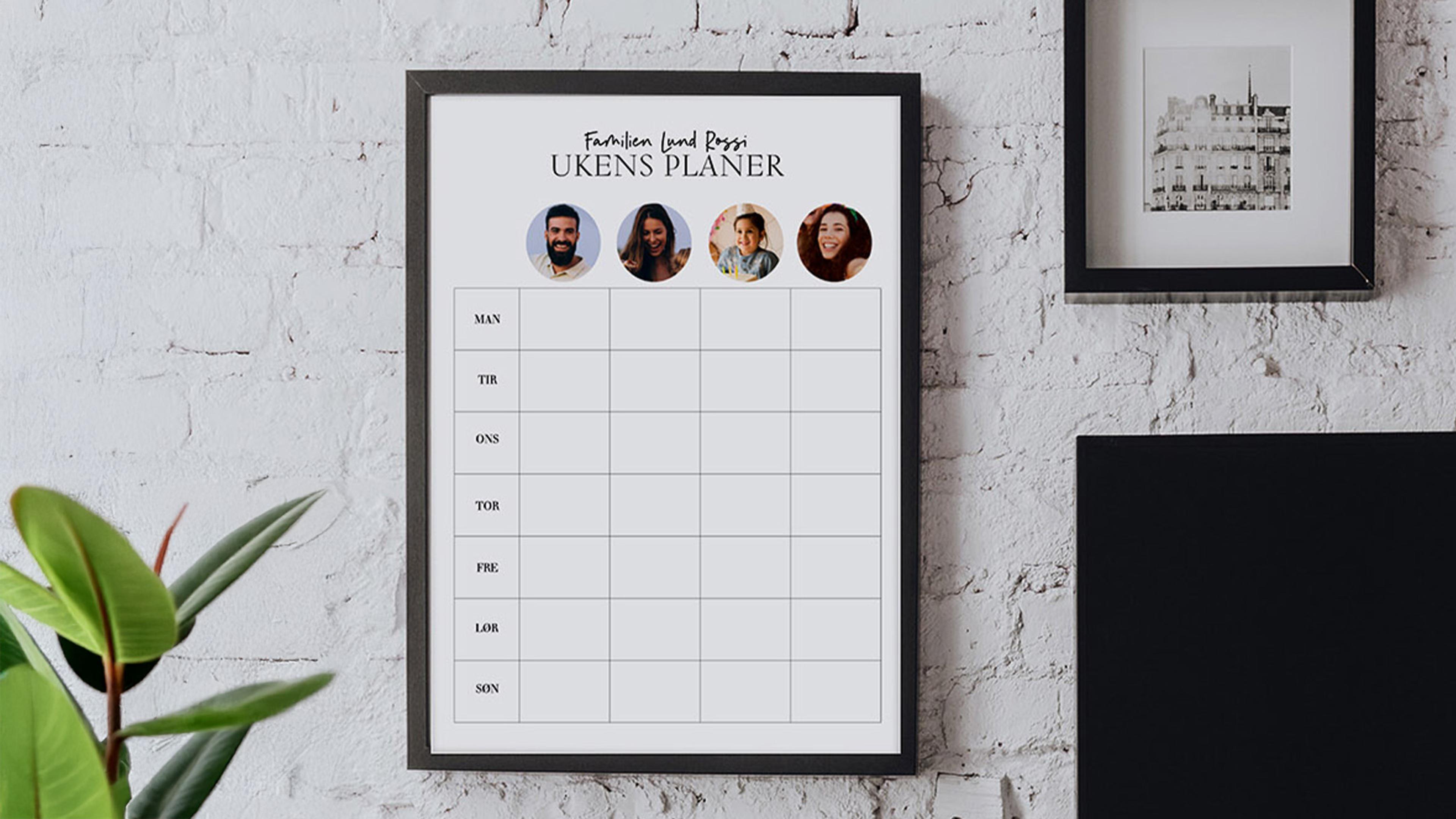 Familieplanlegger med bilder av familiemedlemmene henger på vegg i sort ramme