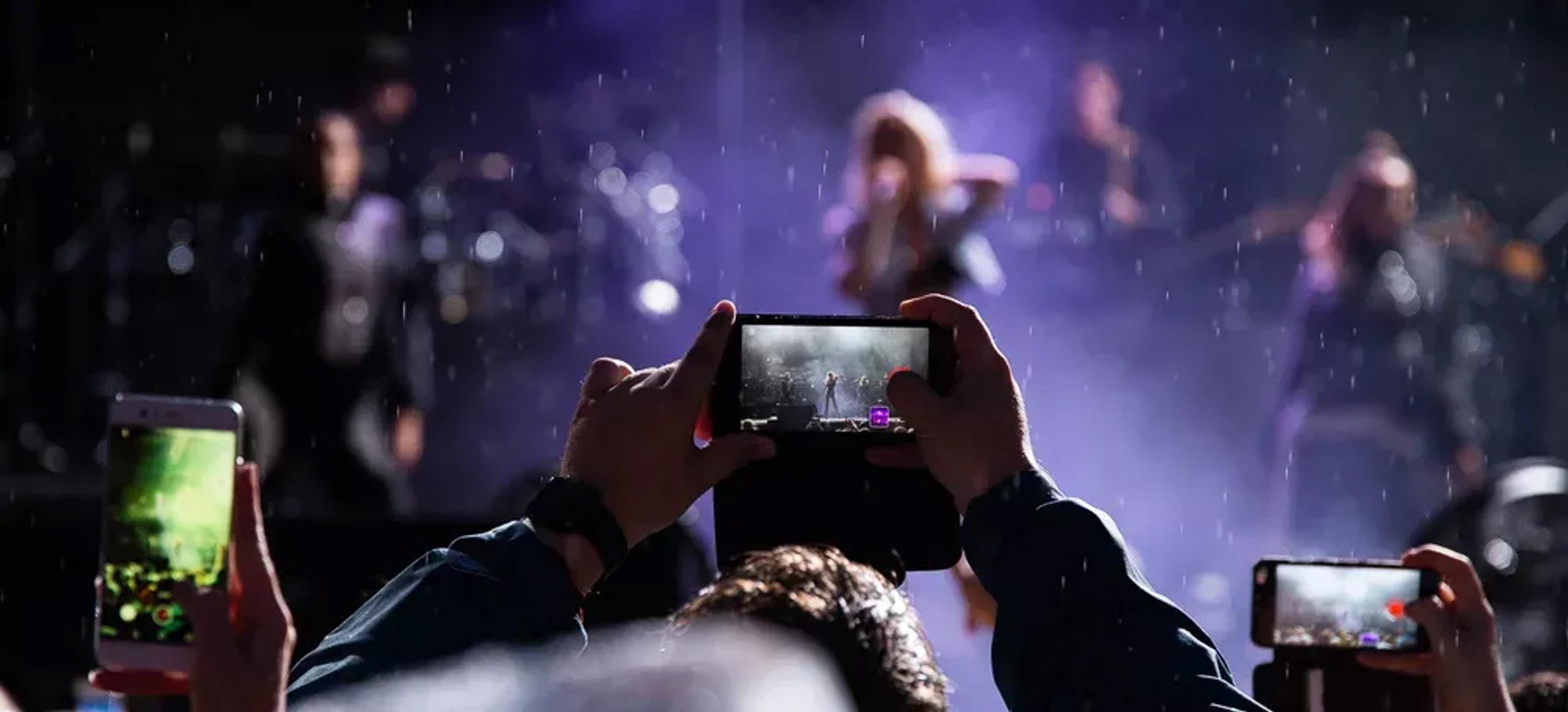 En konsertgjenger tar bilde av scenen med mobilen