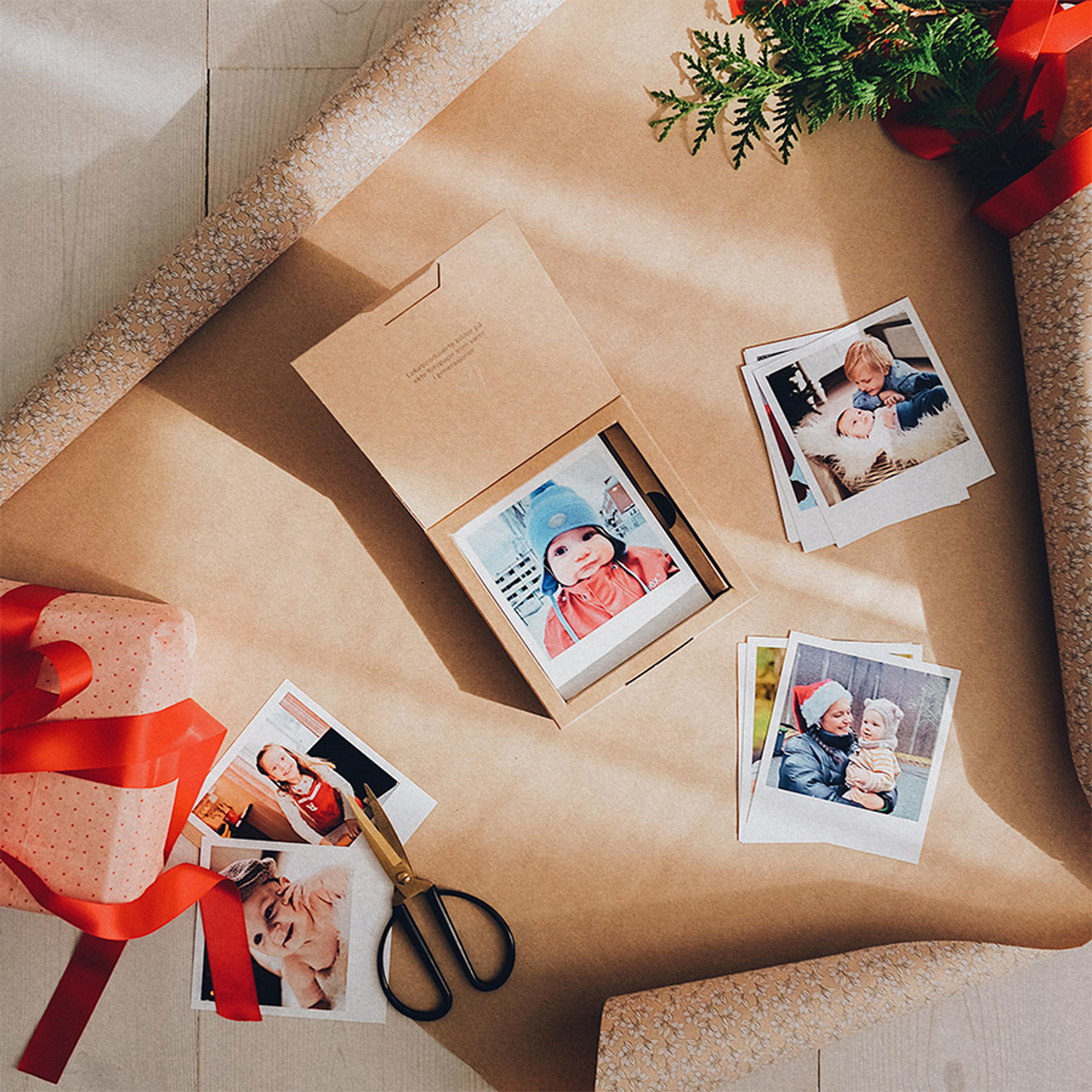 Flere retrobilder ligger på et gavepapir og i en gaveboks