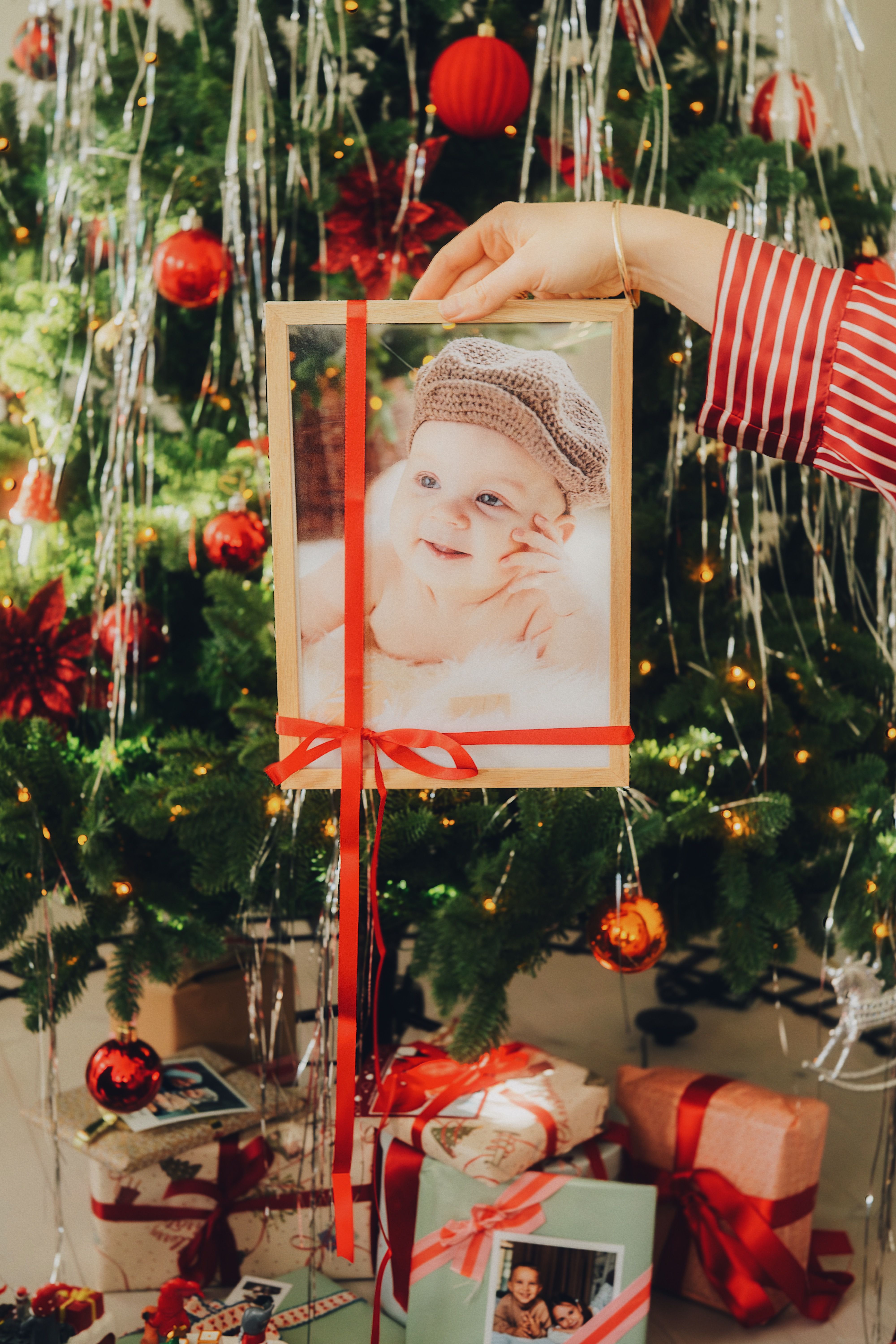 Innrammet bilde med rød sløyfe på holdes opp foran et juletre