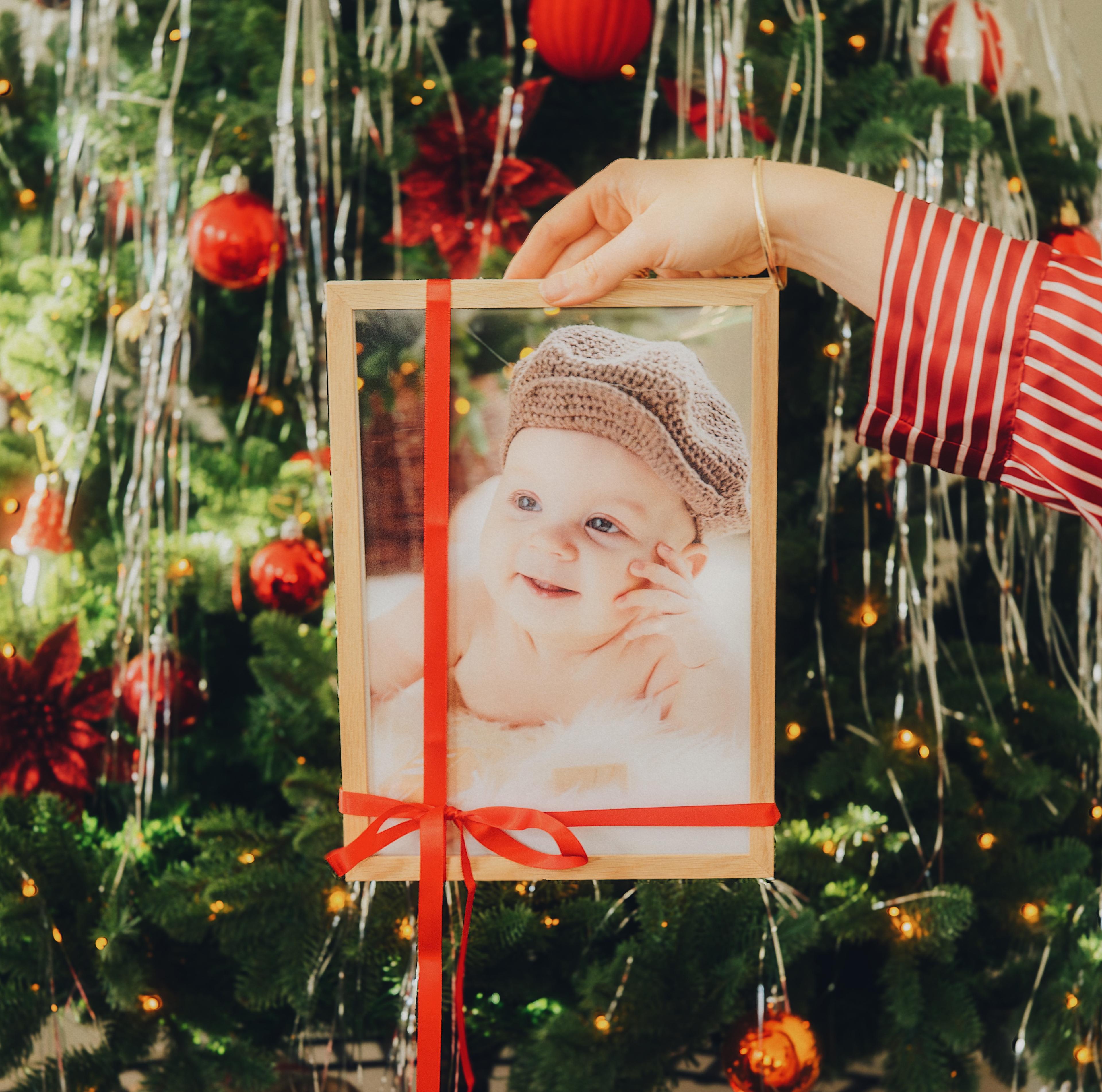 Innrammet bilde med rød sløyfe på holdes opp foran et juletre