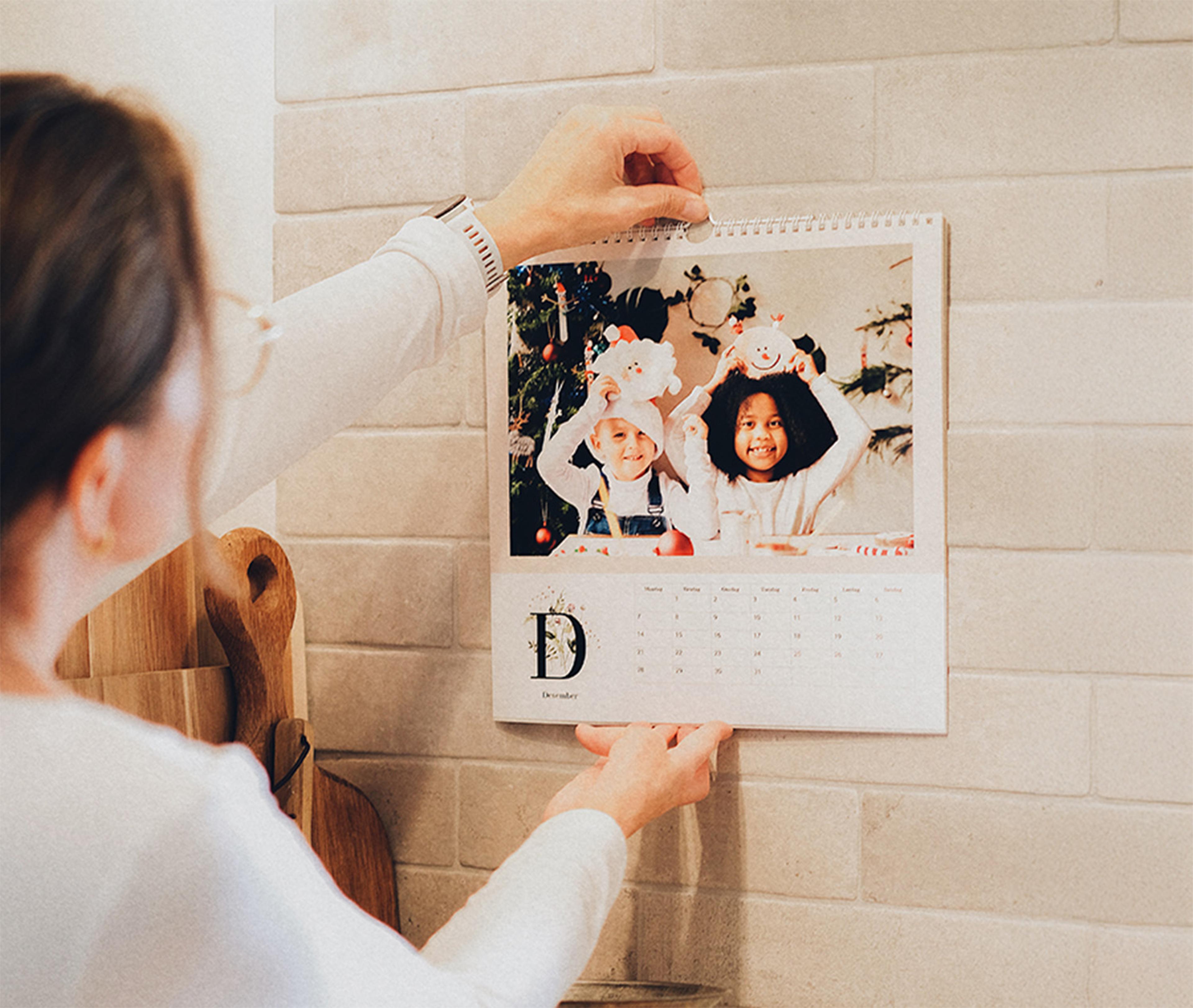 Stor kvadratisk 12 siders kalender henges opp på vegg