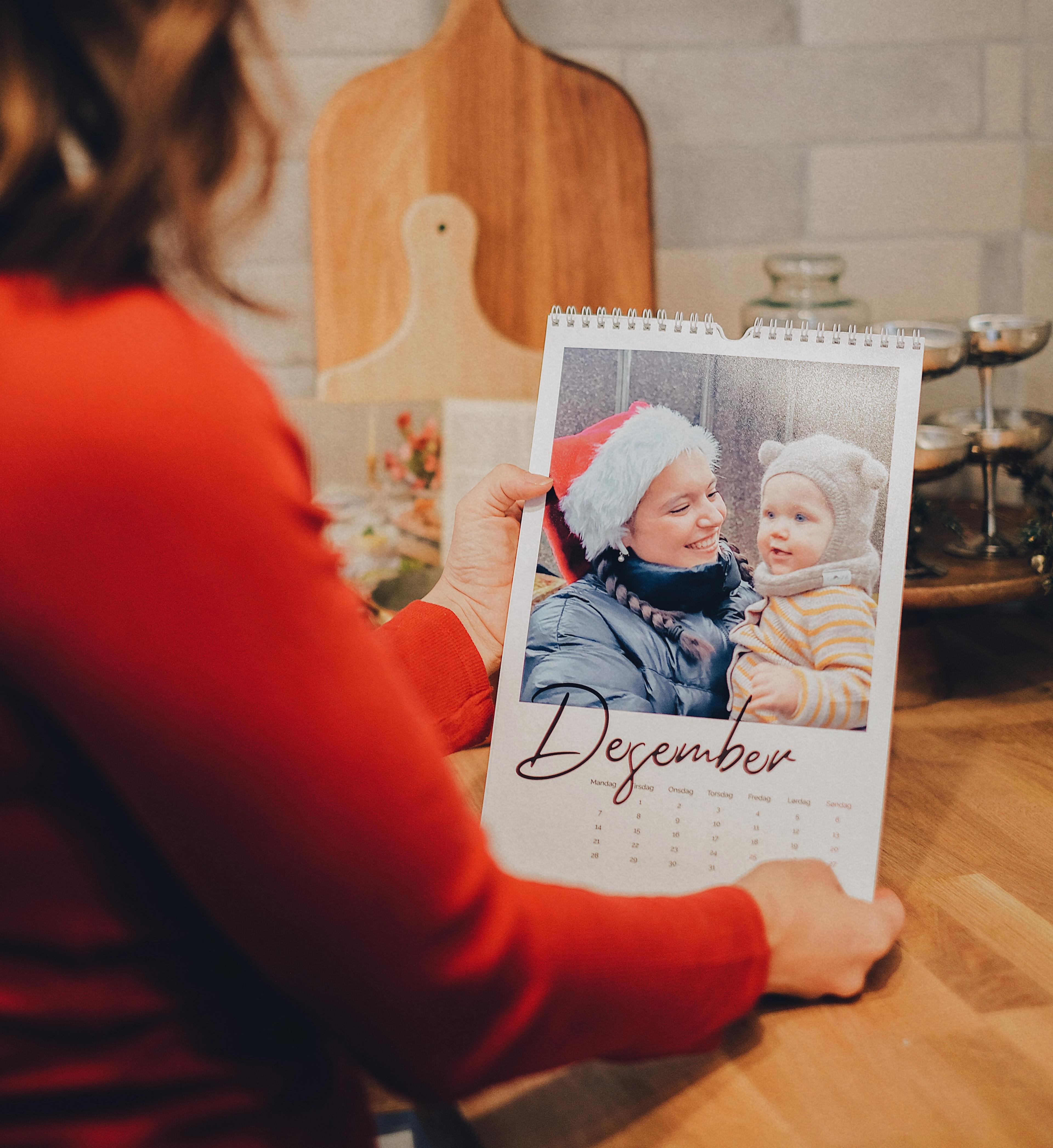Dame som ser på en fotokalender med et stort bilde og teksten desember