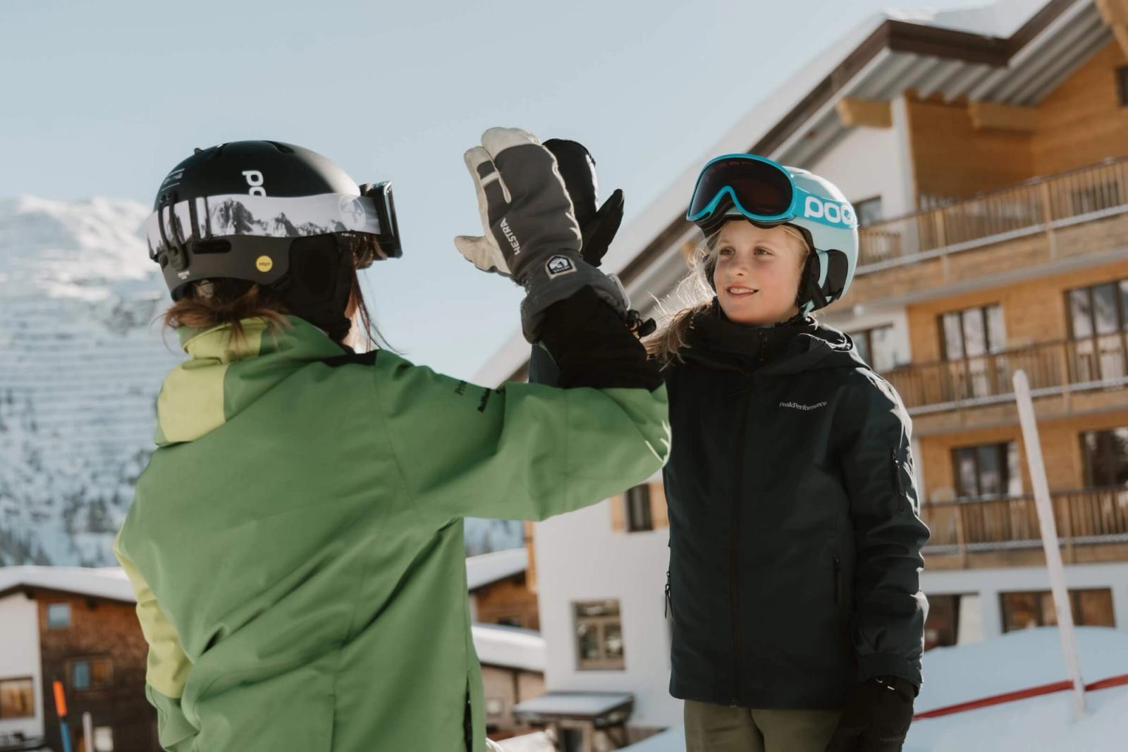 Child and instructor high five during a ski lesson in Lech