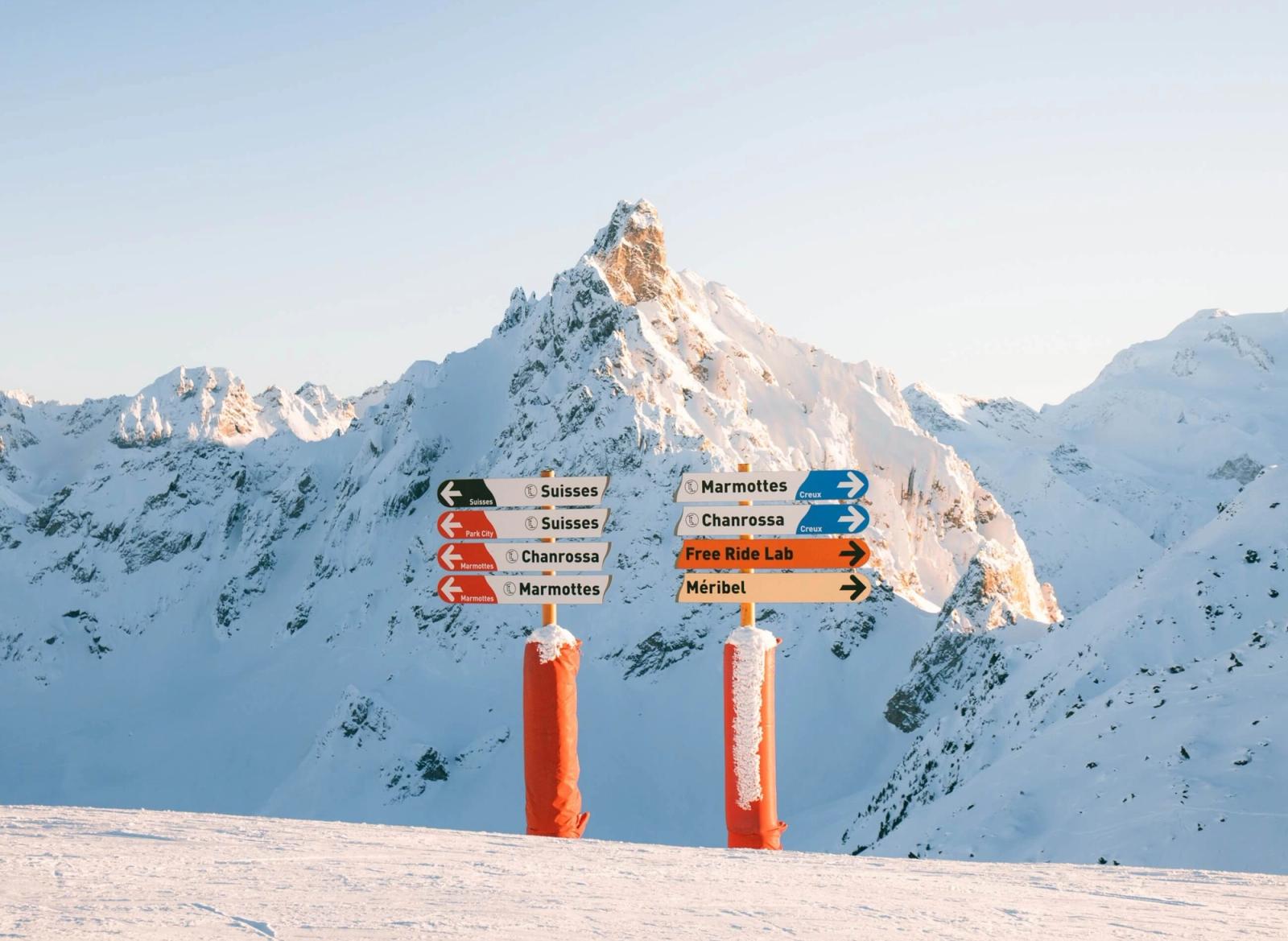 Piste marker signs with a snow-covered mountain behind