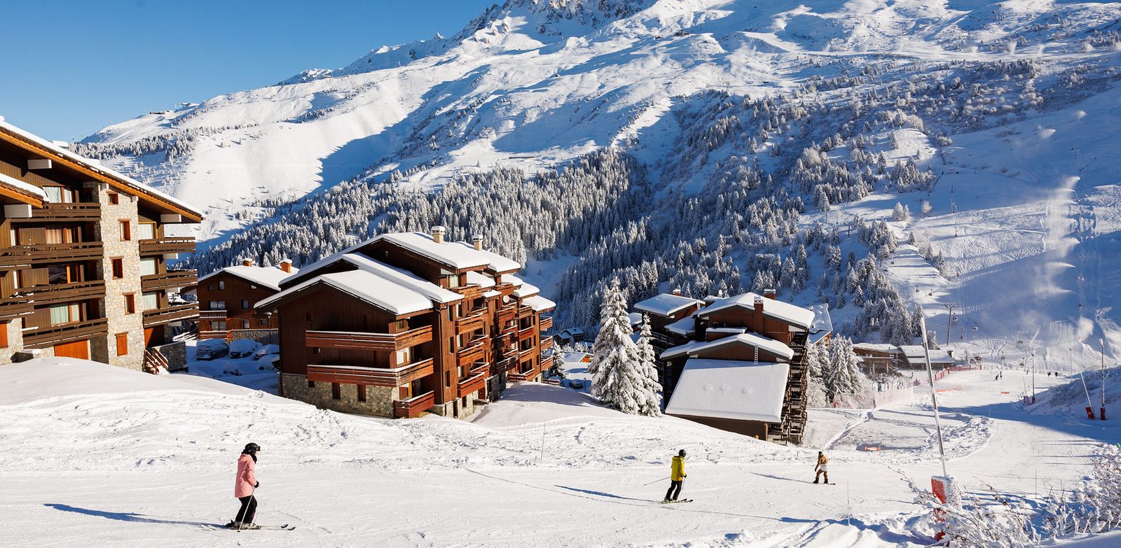Skiers in Meribel with wooden chalets and hotels behind