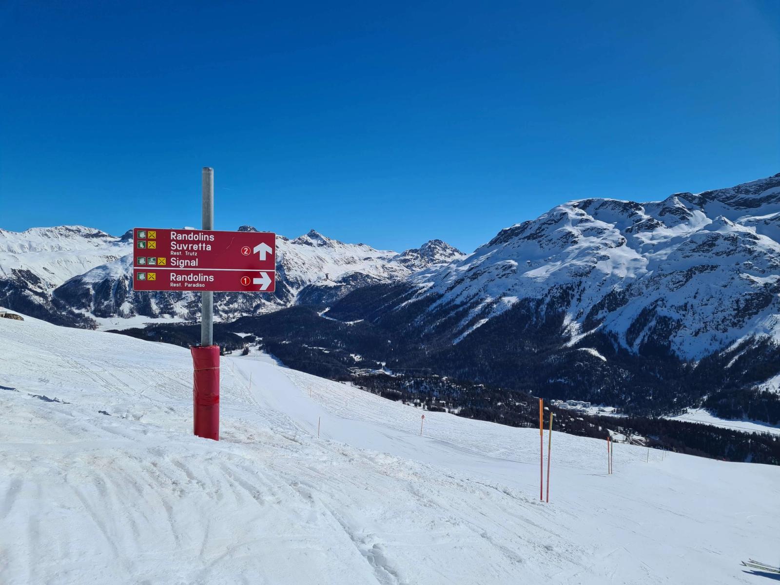 Piste markers in St Moritz with mountain views behind