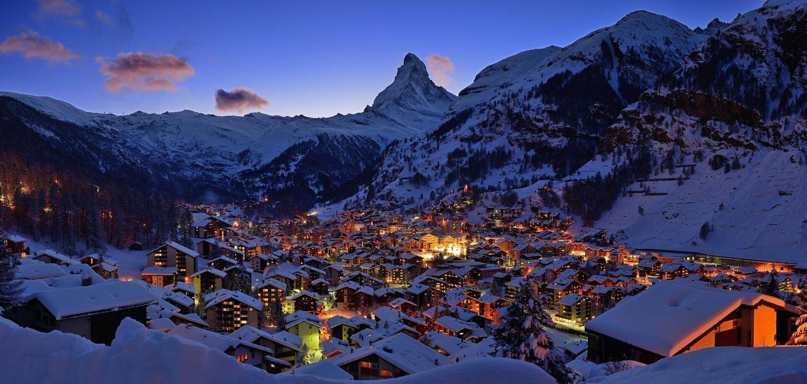 Zermatt village lit up at night, with the Matterhorn ad mountains  in the background