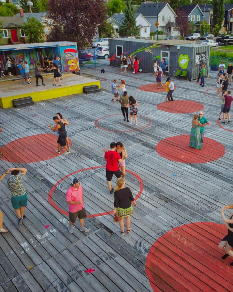 People dance in pairs on brightly-painted circles at an event