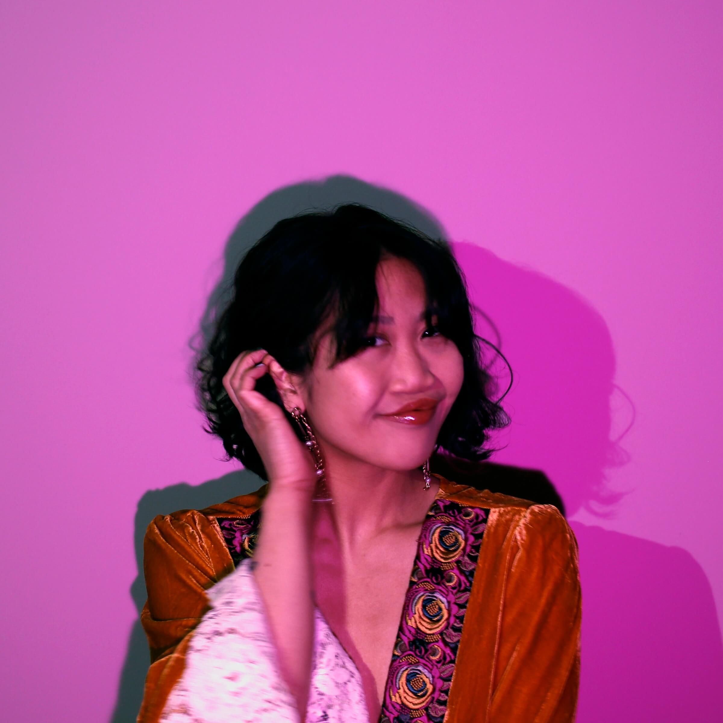 Headshot of Jess Luu in pink lighting