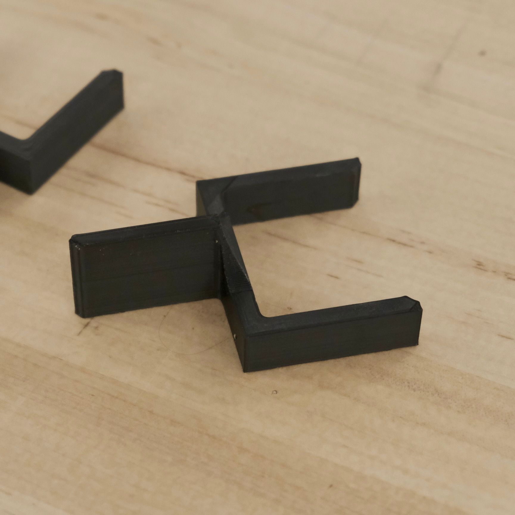 black plastic clip resembling a football goal post laying flat on a wooden table