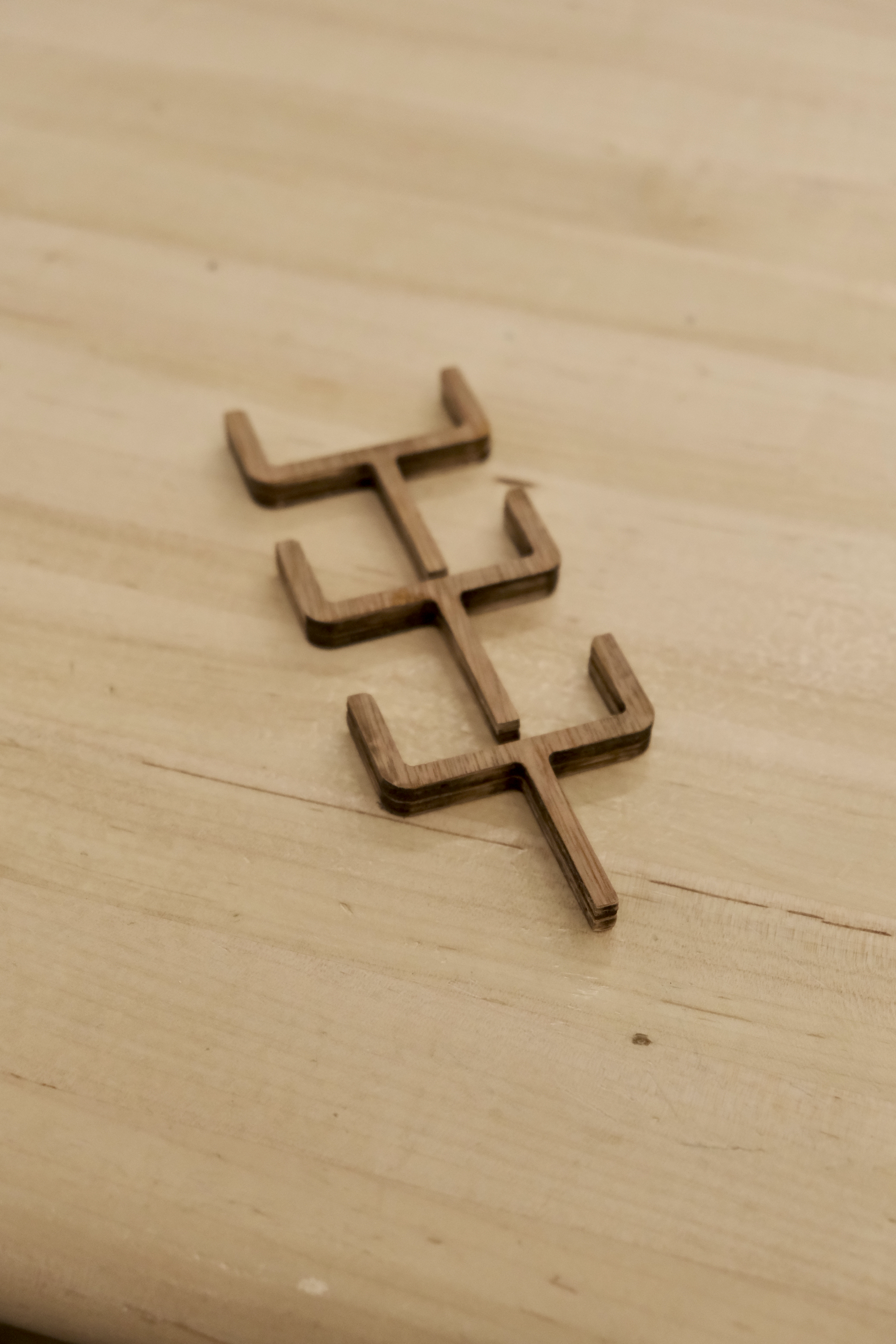 3 laser cut plywood parts designed to hold the power strip. the part has some resemblance to a football goal post
